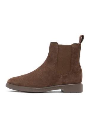 Stivaletto Chelsea in camoscio marrone con pannello laterale elastico e linguetta di tiraggio su suola in gomma bassa, mostrato di profilo.