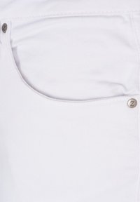 Tela de mezclilla blanca mostrando el detalle del bolsillo con un acento metálico que presenta un logo "Z". La textura es suave con costura visible.