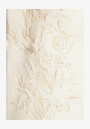 Cremefarbenes Filzmaterial mit aufwändiger Blumenstickerei in sanftem Rosa und Weiß, verziert mit goldenen Pailletten und einem runden Stoffknopf.