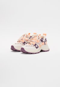 Sneakers con tomaia in rete color crema e arancione chiaro, con dettagli viola e suola chunky. Include lacci e linguette.