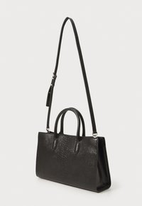 Sac à main noir en cuir embossé, de forme rectangulaire, avec des poignées doubles et une bandoulière amovible. Design épuré.