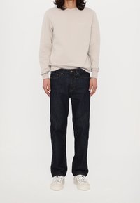 Jasnoszara bluza z okrągłym dekoltem, ciemnoniebieskie jeansy o prostym kroju i białe tenisówki. Prosty design z minimalnymi akcentami.