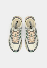 Un paio di scarpe da running Adidas Adizero in beige, grigio e verde, viste dall'alto con i lacci allacciati.