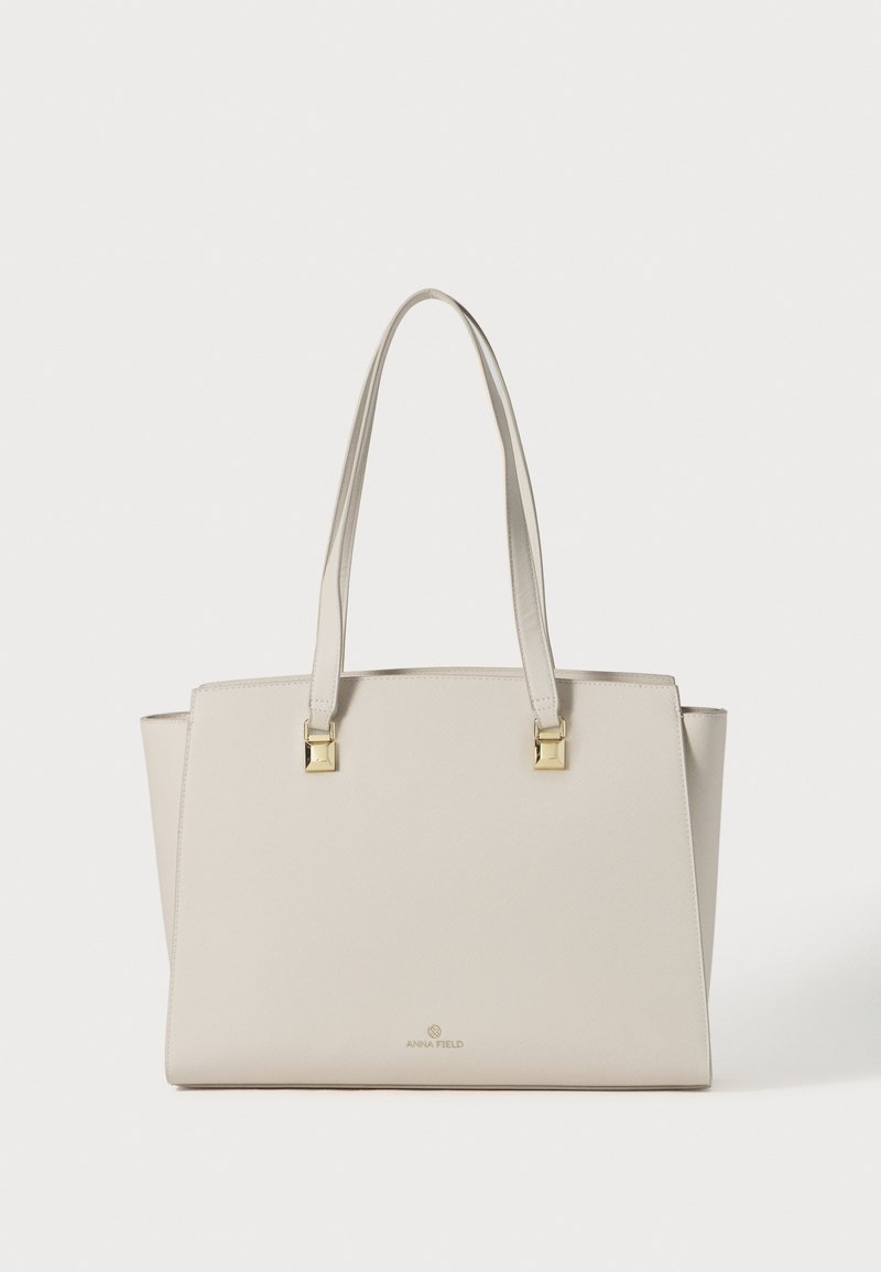 Τσάντα tote από δέρμα στο χρώμα της κρέμας με δύο λουριά ώμου και χρυσές τετράγωνες μεταλλικές λεπτομέρειες.