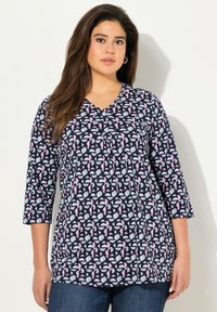 Marineblaue und weiße gemusterte Bluse mit rosa Akzenten, V-Ausschnitt, dreiviertel Ärmeln und Faltenstickerei in der Mitte.