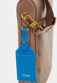 Borsa a tracolla marrone con motivo e finiture in oro, etichetta in pelle blu e finitura testurizzata sui bordi arrotondati.