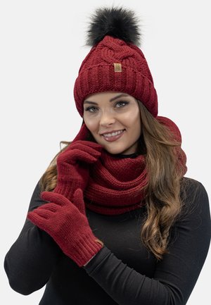 Czerwony dzianinowy beanie z czarnym futrzanym pomponem, pasujący szalik i rękawiczki; teksturowany materiał; dopasowany krój.