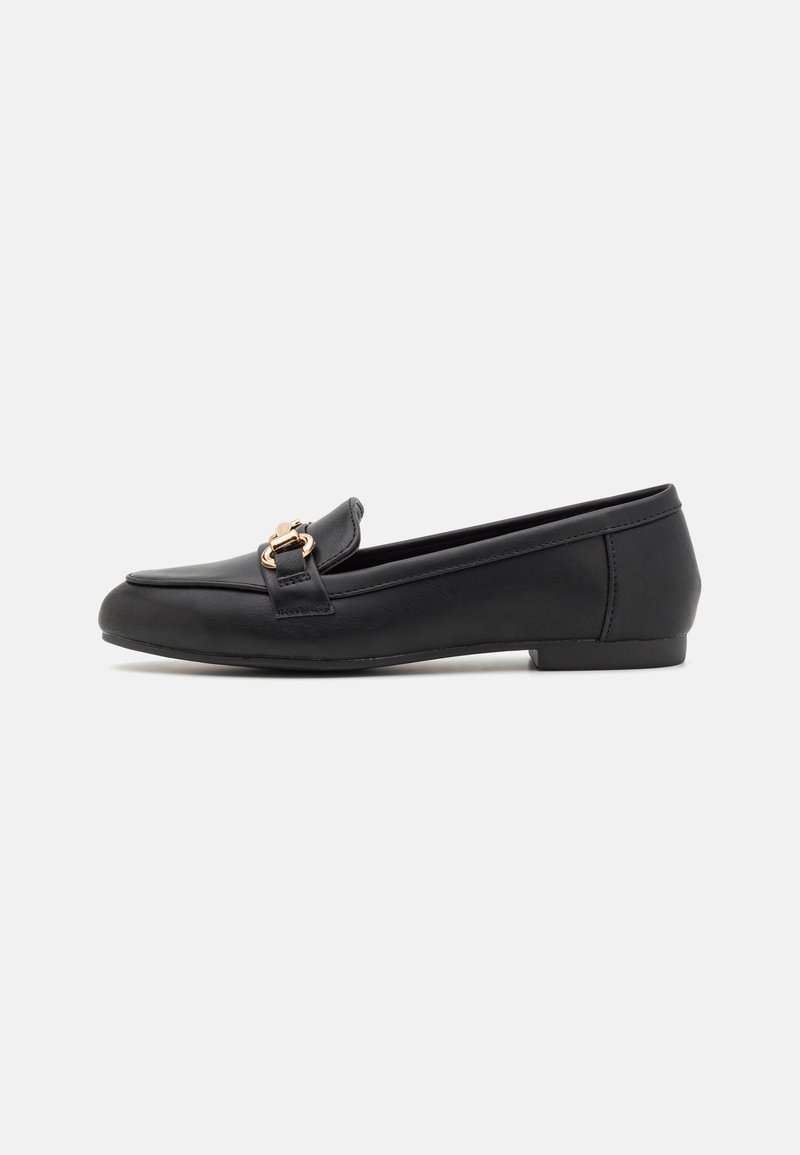 Mocassin plat en cuir noir avec détail de boucle en métal doré et petit talon sur fond blanc, vue de côté.