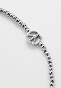 Braccialetto di perle argentate con un charm a forma di simbolo della pace. Perle metalliche lisce disposte in modo uniforme, con una finitura lucida e dettagli minimi.