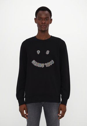 Black long-sleeve sweatshirt featuring a colorful, embroidered smiley face design on the front. Soft fabric and ribbed cuffs.