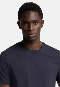 Mörk marinblå bomullst-shirt med rund halsringning och korta ärmar, med en slät textur och minimalistisk design.