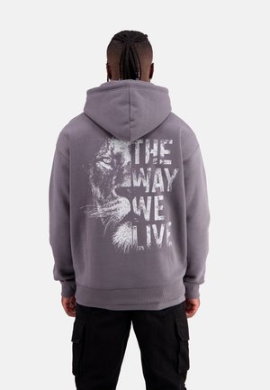 Grey hoodie with a graphic of a lion's face and the text "THE WAY WE LIVE" in white. Features a drawstring hood and ribbed cuffs.