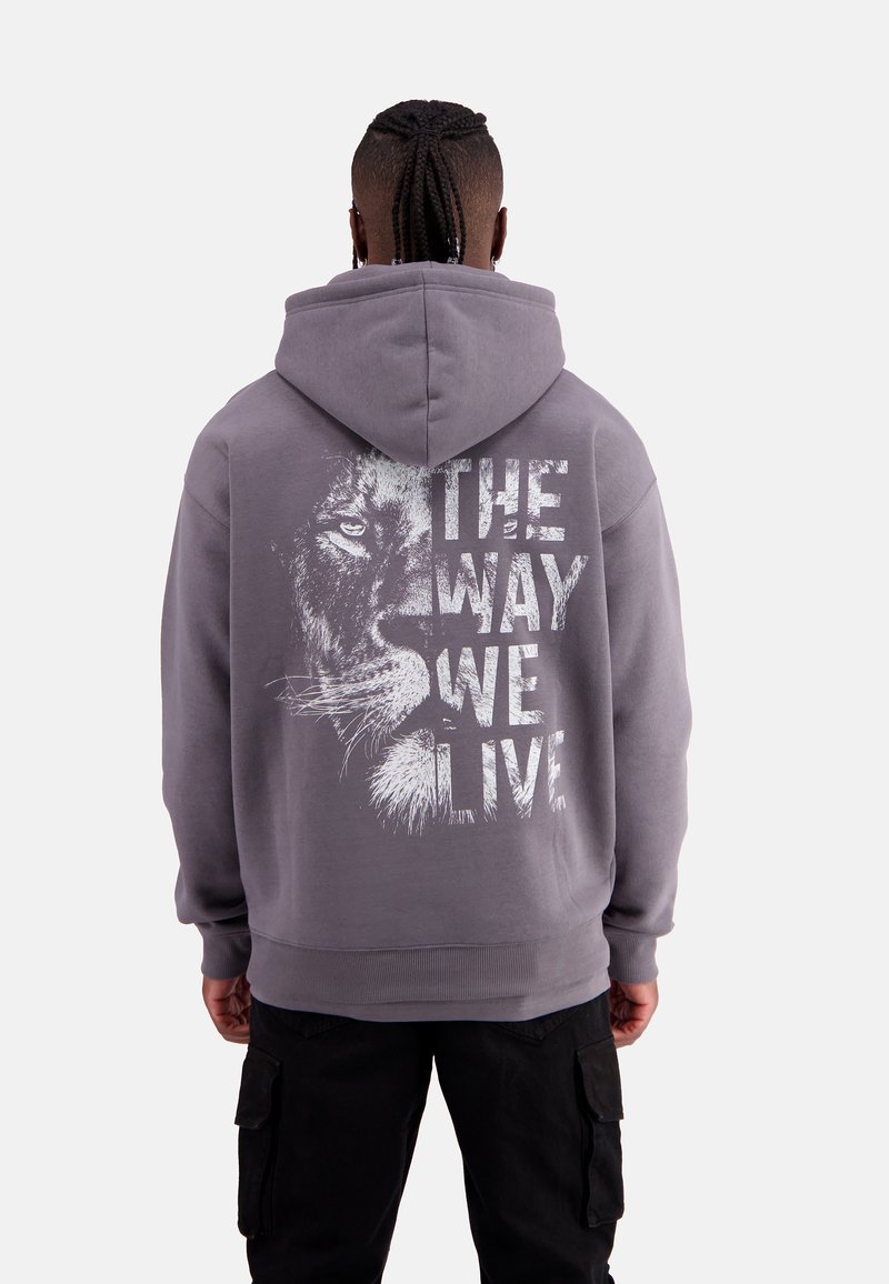 Grey hoodie with a graphic of a lion's face and the text "THE WAY WE LIVE" in white. Features a drawstring hood and ribbed cuffs.