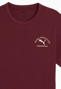 Burgunderfarbenes T-Shirt aus Baumwolle mit Rundhalsausschnitt. Mit gesticktem "PUMA ATHLETICS"-Logo in Creme und dem Gründungsdatum darunter.