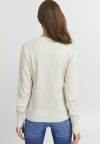 Pulover bej cu mânecă lungă, fabricat dintr-un material tricotat moale. Are un guler rotund, manșete ribbate și un tiv drept. Vedere din spate prezentată.