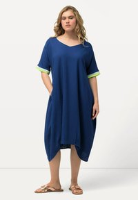 Blauwe jurk met een losse fit, V-hals, korte mouwen met groene accenten en zijzakken. Zacht, lichtgewicht stof met een afgeronde zoom.