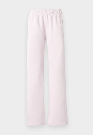 Pantalon de sport rose clair avec une taille élastique, deux poches latérales et un logo réfléchissant blanc près de la hanche gauche. Texture de tissu lisse.