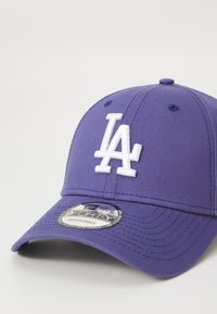 Boné de basebol roxo com um logótipo "LA" em branco bordado na frente, apresentando uma pala curva e uma tira ajustável na parte de trás.