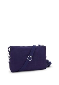 Kleine rechteckige marineblaue Umhängetasche mit verstellbarem Riemen, Reißverschluss und Pompon-Schlüsselanhänger auf weißem Hintergrund.