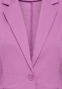 Gros plan d'un blazer lavande avec un col à revers cranté et une fermeture simple à bouton assorti à l'avant.