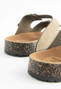 Calzado: tirantes de ante beige y cuero verde, suela de plataforma de corcho y moteada en negro, plantilla texturizada, detalle ajustable de metal.