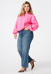 Roze gestreepte blouse met pofmouwen, gecombineerd met blauwe wijde spijkerbroeken en leopardenprint hakken. Subtiele textuur in de stof.