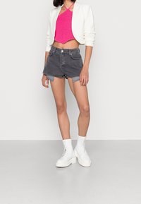 Chaqueta blanca corta, top de hilo rosa con cuello halter, pantalones cortos de mezclilla gris con bordes deshilachados y botas blancas con cordones hasta el tobillo y suelas gruesas.