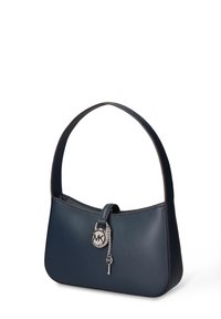 Marineblauwe leren handtas met een afgeronde vorm, korte handgreep en een zilveren sleutelhanger met logo. Soepele textuur en minimalistisch ontwerp.