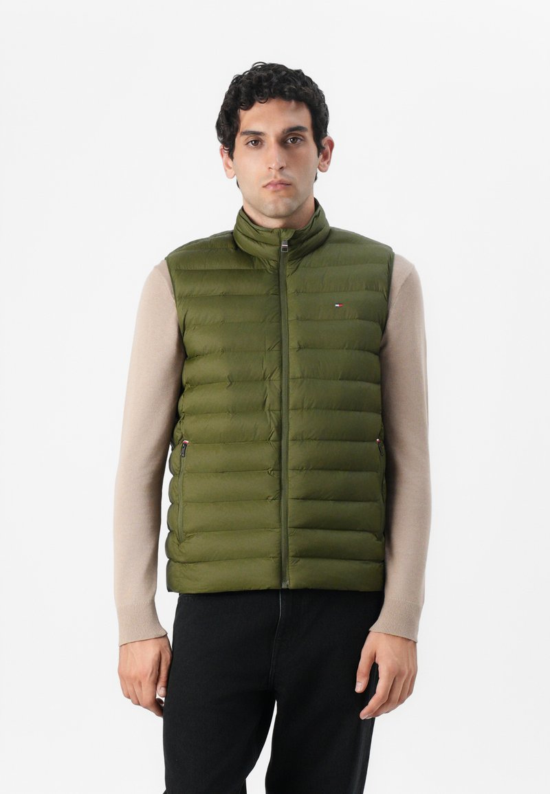 Gilet imbottito verde oliva con colletto alto, chiusura lampo frontale e due tasche laterali. Presenta cuciture orizzontali e un piccolo logo sul petto.