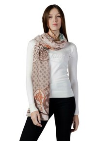 Sciarpa marrone chiaro con motivi geometrici in arancione e verde acqua, drappeggiata intorno al collo di una modella, indossata sopra un maglione bianco. Tessuto morbido e liscio.