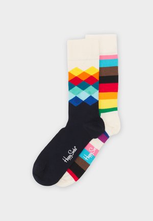 Colorful socks featuring a navy base with a diamond pattern in vibrant hues and a white sock with multicolored stripes. Cotton blend material.