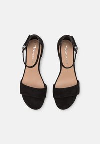 Zwarte suède hak-sandalen met een brede teenband, een enkelband met een zilveren gespsluiting en een gladde beige binnenzool.