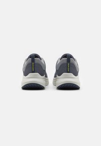 Scarpe da ginnastica navy e grigie con tomaia in rete strutturata, intersuola bianca ammortizzata e logo giallo a contrasto sul tallone.