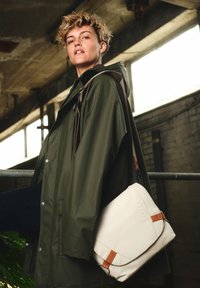 Asgrauwe boodschappentas met bruine leren accenten. De tas heeft een omslagklep en een verstelbare schouderriem.