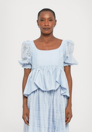 Vaaleansininen mekko, jossa on neliönmuotoinen pääntie, puffatut lyhyet hihat ja peplum-muotoilu. Kankaan pinnassa on hienovarainen ruutukuosi ja pehmeä tekstuuri.