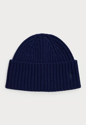 Kootud tumesinine beanie, millel on ribikujuline tekstuur ja kokkuvolditav äär. Küljel on väike, sarnases värvitoonis tikitud logo.