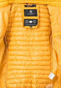 Yellow puffer jacket interior with quilted texture, brands label, and tag detailing. Smooth, shiny fabric, zippered pocket on the left side.