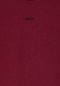 T-shirt bordeaux a maniche corte realizzata in tessuto morbido, con logo "FREDDY" ricamato in nero sul petto. Tessuto liscio, scollatura rotonda standard.