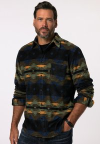 Flannel skjorte med et geometrisk mønster i sort, grøn og blå med orange detaljer, lange ærmer og en brystlomme. Struktureret stof.