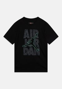 Camiseta de algodón negra con un estampado gráfico de "AIR JORDAN" en gris texturizado y un contorno verde de un jugador de baloncesto.
