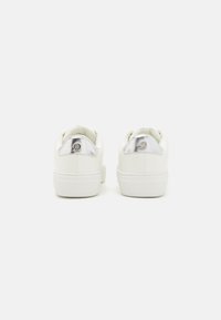 Baskets en cuir blanc à texture lisse, forme arrondie et accent argenté au talon. Semelle en caoutchouc blanche plate avec une prise texturée.