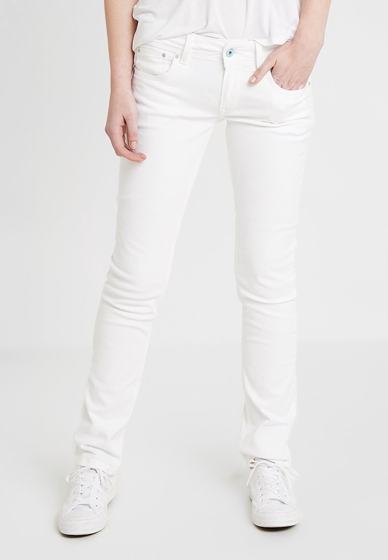 Jeans de mezclilla blanca con corte slim, diseño de cinco bolsillos y un botón azul claro en la cintura. Combinados con zapatillas blancas.