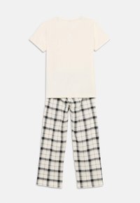 Λευκό κοντομάνικο μπλουζάκι συνδυασμένο με άνετο, καρό παντελόνι σε λευκό και μαύρο, με σχέδιο καρό και απαλό ύφασμα.