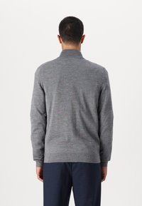 Šedý pletený svetr s vysokým límcem, dlouhými rukávy a žebrovanými detaily na manžetách a lemu. Hladká textura, minimalistický design.