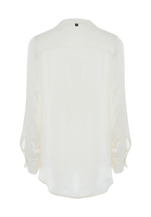 Blouse crème avec des manches longues légèrement bouffantes, un ourlet arrondi et un col simple. Texture lisse, sans motifs ni accents visibles.