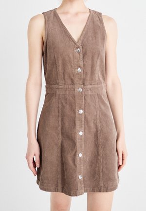 Hihaton ruskea ribbineulemekko V-pääntiellä ja edessä hopeisilla napeilla, istuva vyötärö, yllään seisova henkilö.