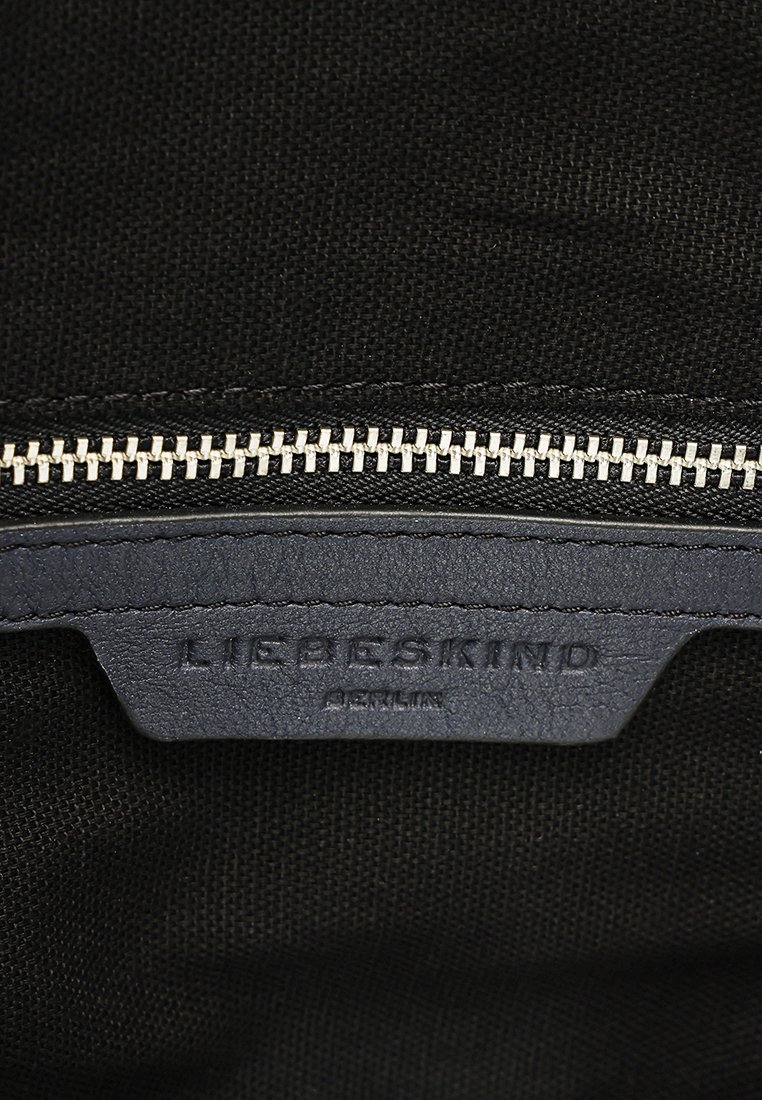 Wnętrze czarnej torby na ramię z srebrnym zamkiem błyskawicznym. Posiada fakturowaną, ciemnoniebieską skórzaną metkę z wytłoczonym napisem "LIEBESKIND BERLIN".