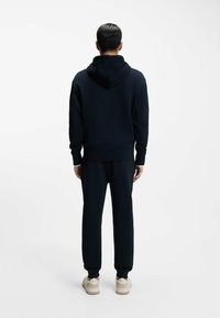 Navy blue hoodie and matching sweatpants set, made of soft fabric. Features a hood, ribbed cuffs, and tapered leg design.