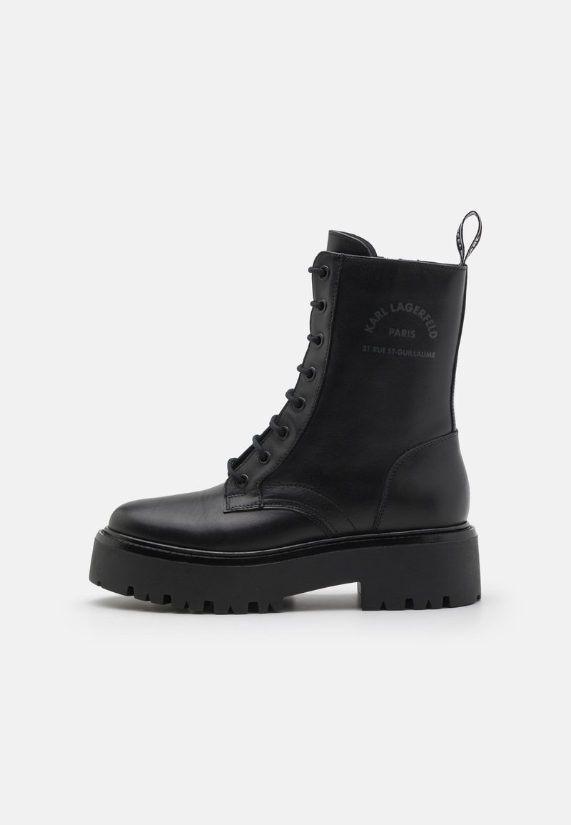 Bottes noires en cuir à bout rond, avec un design à lacets, semelle en caoutchouc épaisse, et détails en logo embossé subtils sur le côté.