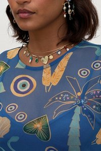 Caurskatīgs zils tops ar krāsainu tropu rakstu, kas ietver lapu, apļu un čaulu motīvus. Smalkas slāņotas kaklarotas un auskari.